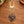 Copper heart charm with a hummingbird on a gold swivel clasp, on a wooden table