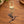 Copper hummingbird charm on a gold swivel clasp, on a wooden table