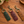 Pop's leather hummingbird keychains in forest green, burgundy and chestnut brown on a wooden table
