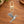 Pewter hummingbird charm on a gold swivel clasp, on a wooden table