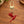 Red hummingbird charm on a gold swivel clasp, on a wooden table