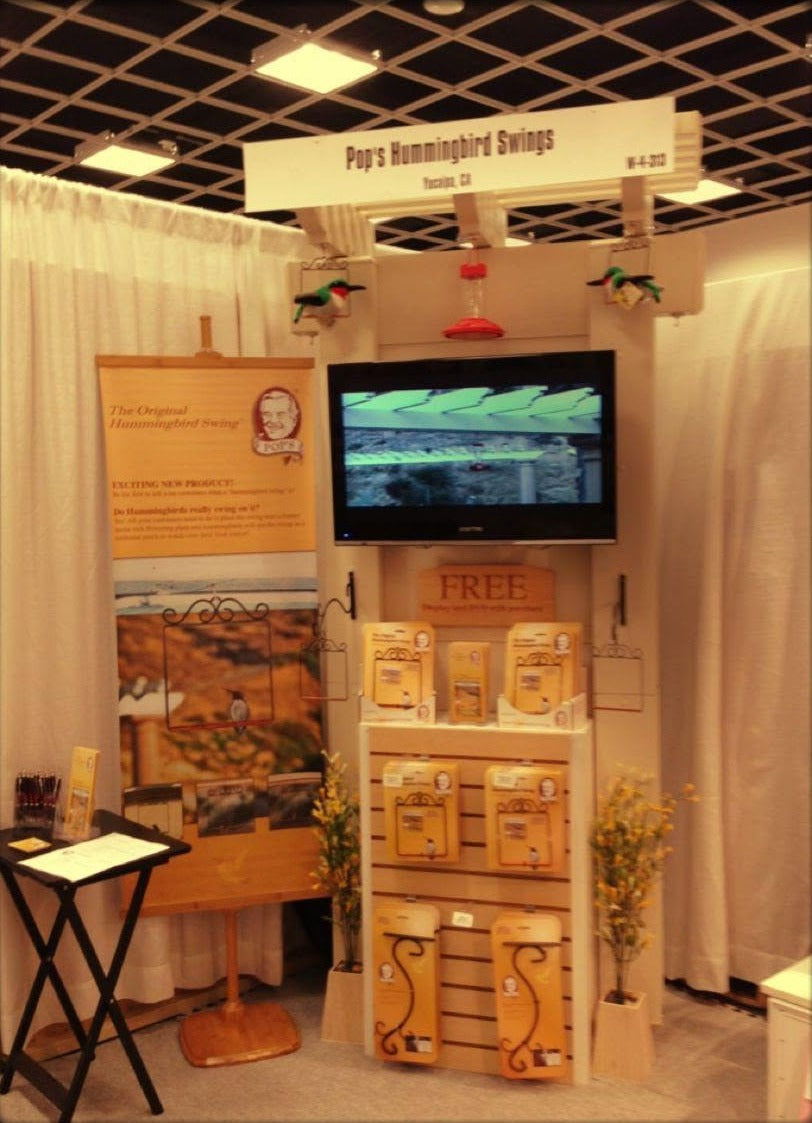 Pop's Hummingbird Swings early trade show booth from Yucaipa, California, with a TV, banner and gold swing packages