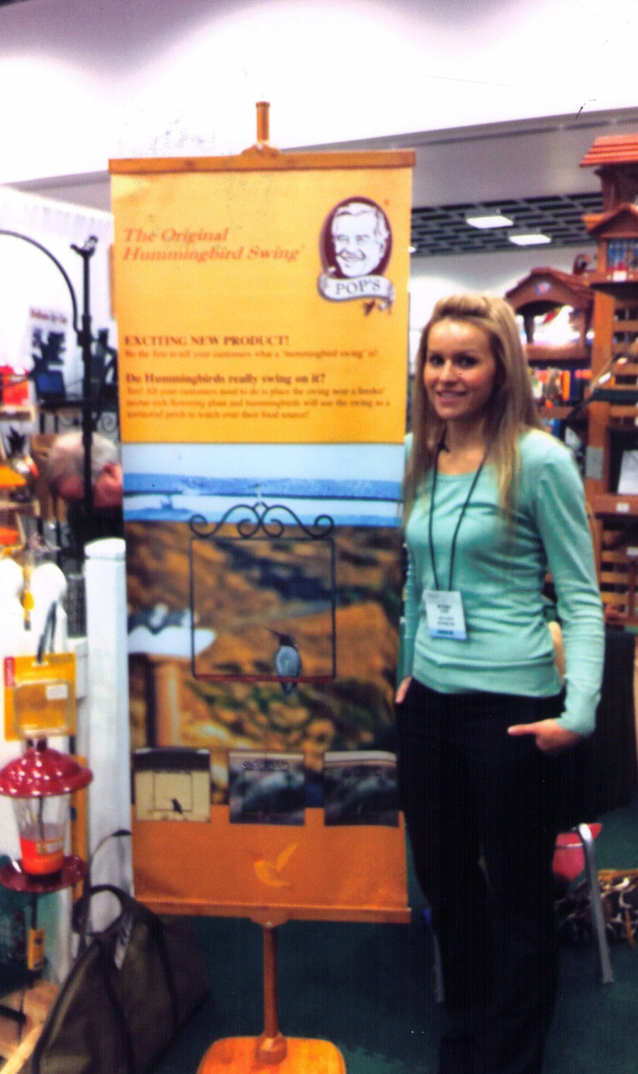 Bethany Sloan beside a Pop's Original Hummingbird Swing banner at a 2011 trade show
